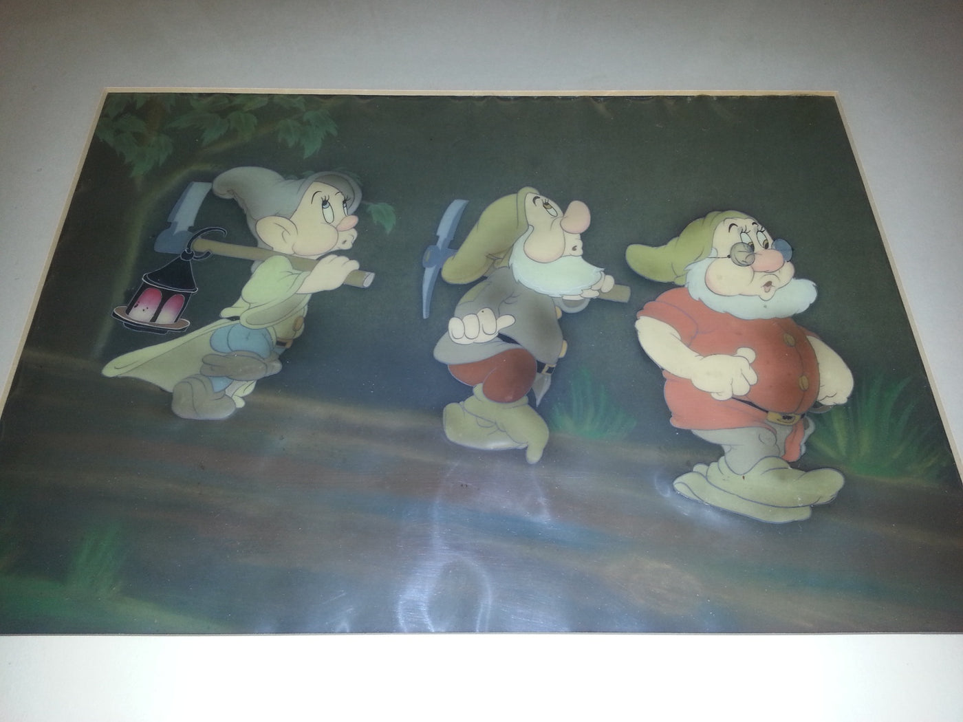 Original Walt Disney Production Cel on Courvoisier Background from Snow White and the Seven Dwarfs featuring Dopey, Sneezy and Doc
