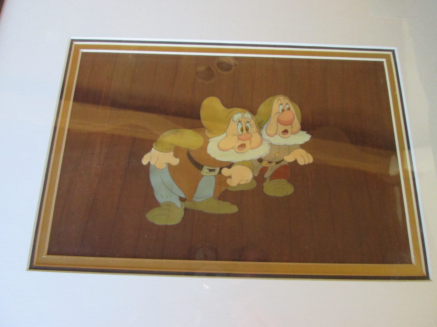 Original Walt Disney Production Cel on Custom Woodgrain Background from Snow White and the Seven Dwarfs featuring Happy and Sneezy